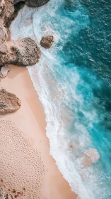 Vertical aerial view of rocky shoreline and sand beach.
