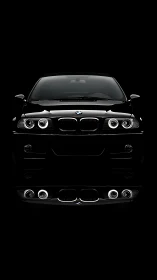 Front-lit black sedan with halo headlights on black background
