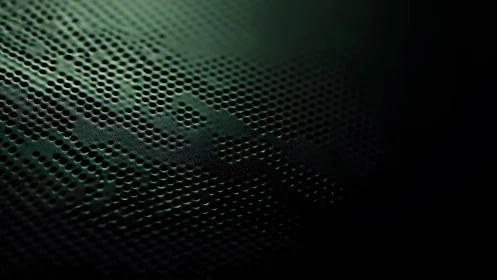 Macro shot of perforated metal surface with dark green lighting.