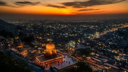 Illuminated domed complex above dense city at sunset.