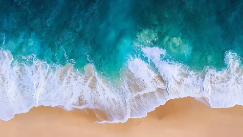 Top view of turquoise ocean surf on smooth sandy shore.
