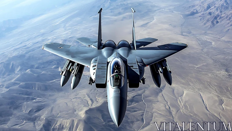 Twin‑engine strike fighter with underwing payload over arid terrain