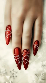 Red stiletto nails with silver patterns on pale hand.