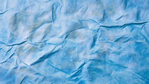 Textured blue crumpled surface with soft photographic lighting.