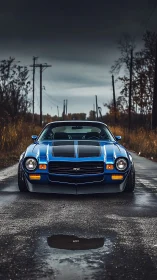 Low-slung blue muscle car dominates a moody rural road