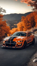 Orange sports car on mountain road in vivid autumn forest.