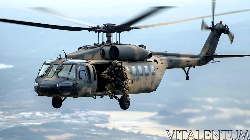 Military helicopter carries armed soldier in open side doorway
