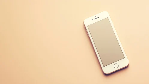 White iPhone Resting on a Warm, Peachy Background.