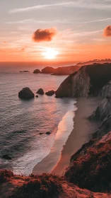 Coastal cliffs and shoreline at sunset under orange sky.