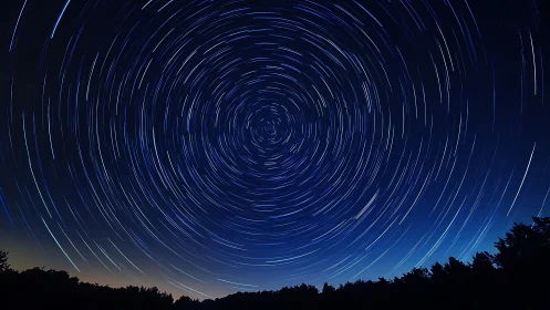 Star trails swirl over a dark forest in night sky photography.
