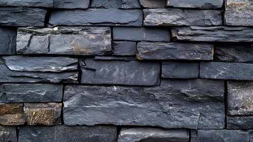 Close-Up of Stacked Black Slate Stone Wall with Natural Texture.