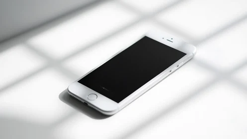 White iPhone with Black Screen on Sunlit Surface.