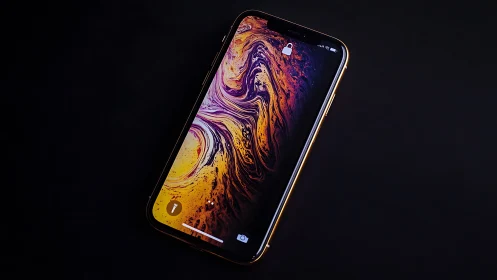 iPhone XS Max displaying swirling liquid marble digital wallpaper on black background.