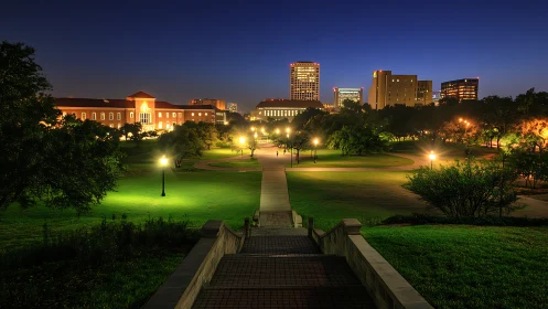 Illuminated campus park leads toward distant city skyline