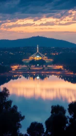 Canberra&rsquo;s parliament glows at dusk above mirrored lake.