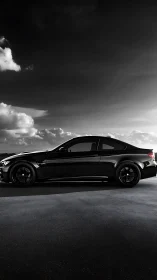 Side profile of black coupe on empty road at dusk sky.