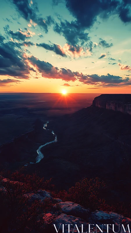 Sunset river winds through dramatic canyon under vivid sky.