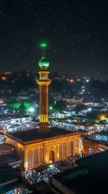 Illuminated mosque minaret above crowded urban night market.