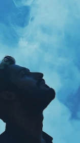 Silhouetted dreamer leans into a sky of drifting ghost-blue mist