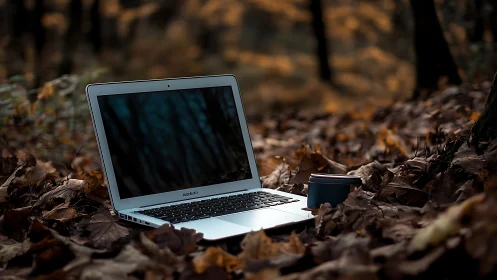 Ultrabook laptop with travel mug on autumn forest leaf floor