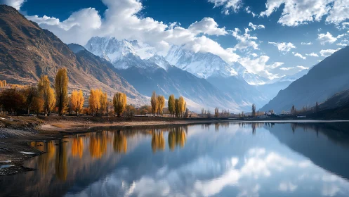 Mountain lake with autumn trees and snow covered peaks.
