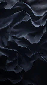 Translucent dark fabric folds form layered flowing waves