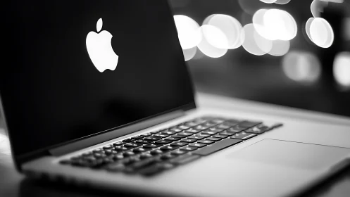 Backlit aluminum laptop with illuminated logo and bokeh background
