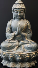 Serene Buddha statue in prayerful meditation on lotus pedestal.