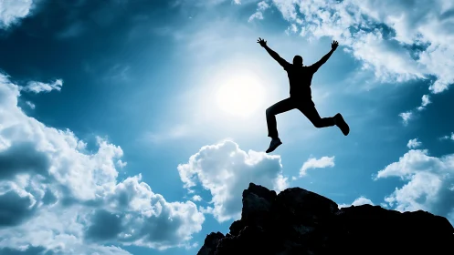 Silhouette leaps from rocky peak into radiant open sky.