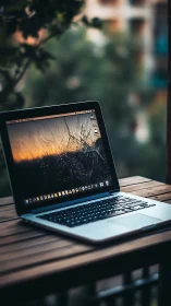 Cracked laptop screen glows at dusk on a wooden balcony