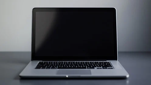 Sleek silver laptop with blank screen on gray desk surface.