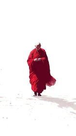 Gentle monk in red robes walking through quiet white space.
