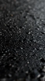 Glistening wet asphalt surface shimmers in soft low light