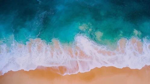 Aerial view of turquoise waves meeting sandy shoreline.
