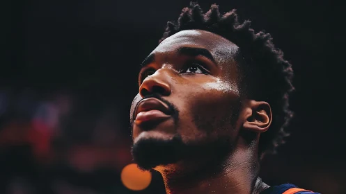 Basketball player gazes upward under arena lights before game