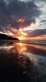 Sunset light reflects across wet tidal sand and cloud layer