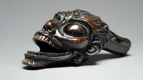 Carved wooden demon head sculpture rests on neutral surface