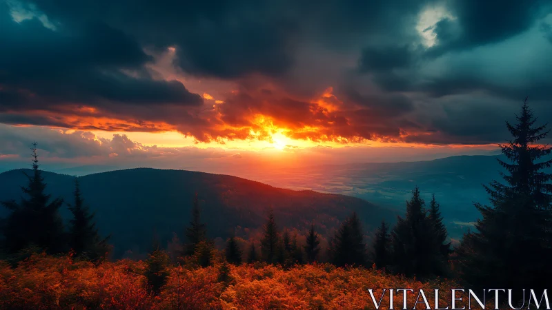 Fiery sunset over dark forested mountains and valley.