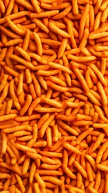 Uniform arrangement of orange cheese snack puffs viewed close.