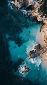 Rocky shoreline meets shallow turquoise water in aerial view