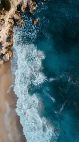 Vertical aerial coastline with waves impacting sandy beach edge