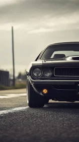 Front view of classic black muscle car on empty roadway.