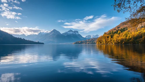 Mountain lake reflects autumn forest under clear blue sky