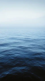 Calm open sea under pale sky with gentle blue waves.