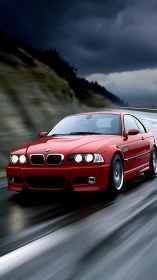 Red BMW coupe travels on wet roadway under overcast sky