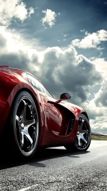 Red sports car on wet track under dramatic storm clouds.