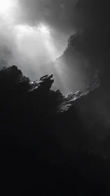 Monochrome cavern shaft with dramatic light beams overhead.