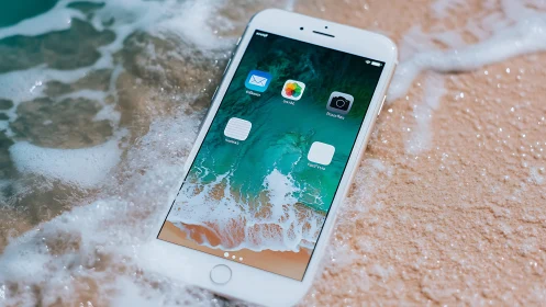 White iPhone at Shoreline: Digital Device Meets Ocean Waves