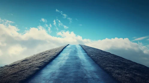 Wet hilltop road rising toward bright blue clouded sky.