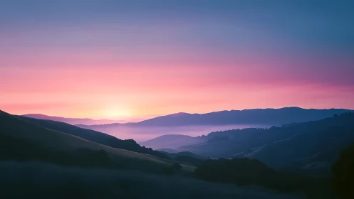 Pastel sunrise light washes over layered mountain ridges.